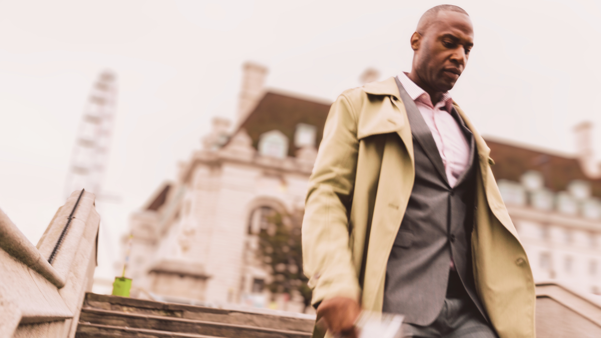 Man in business attire walking down outdoor steps, looking down in a reflective moment