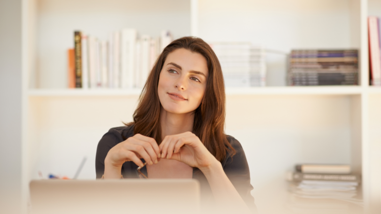 Thoughtful professional woman reflecting at her desk on passion, purpose, and creating greater alignment in her work and life.